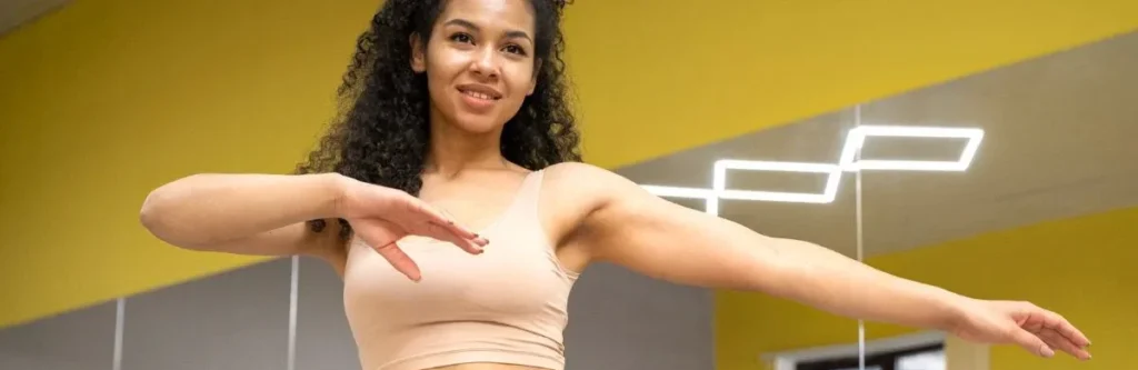 Participants smiling and following an energetic Zumba instructor in a fitness studio.